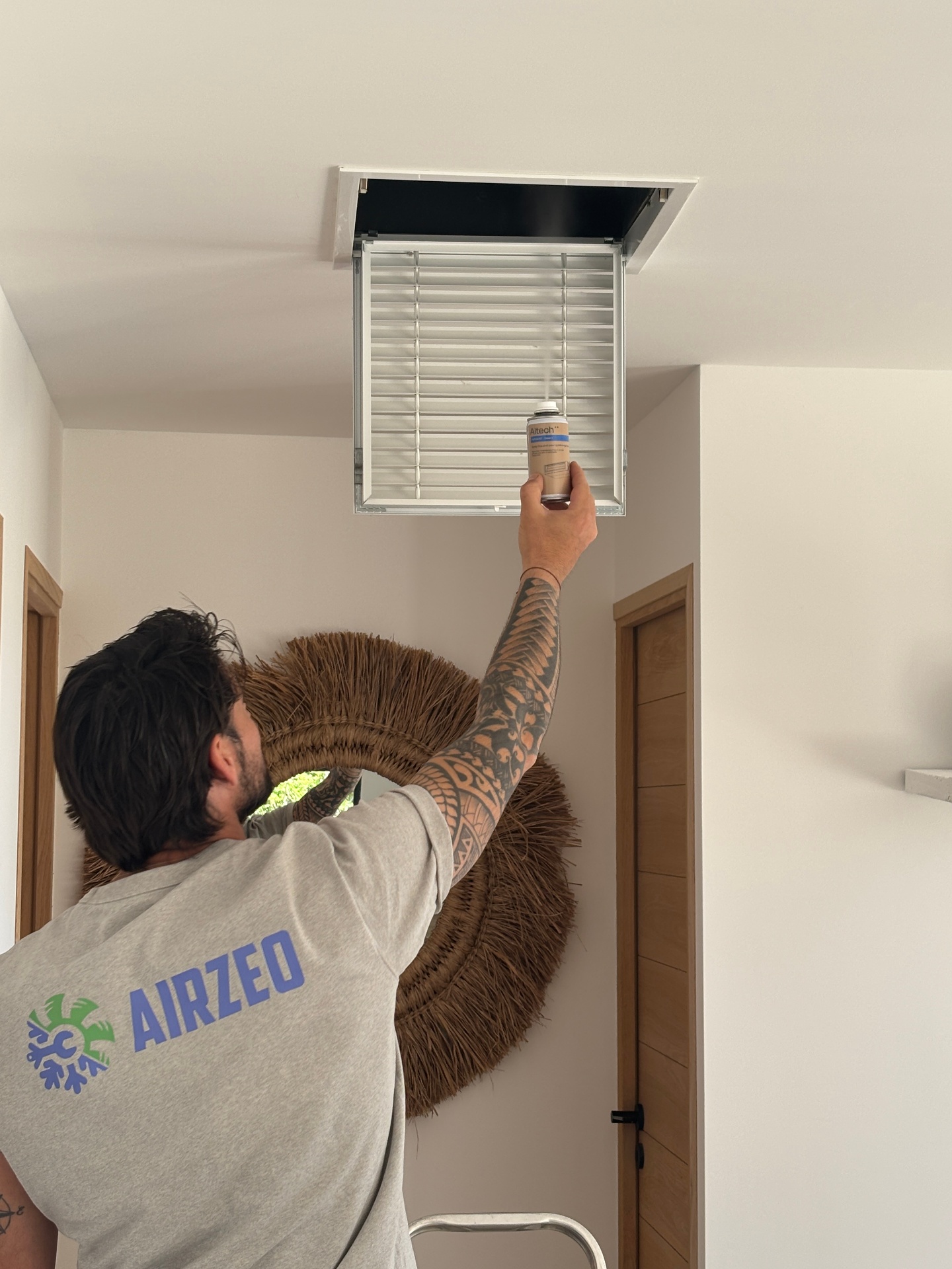 Technicien Airzeo réalisant l'entretien d'une bouche de climatisation gainable dans une maison en PACA (Var et Bouches-du-Rhône)